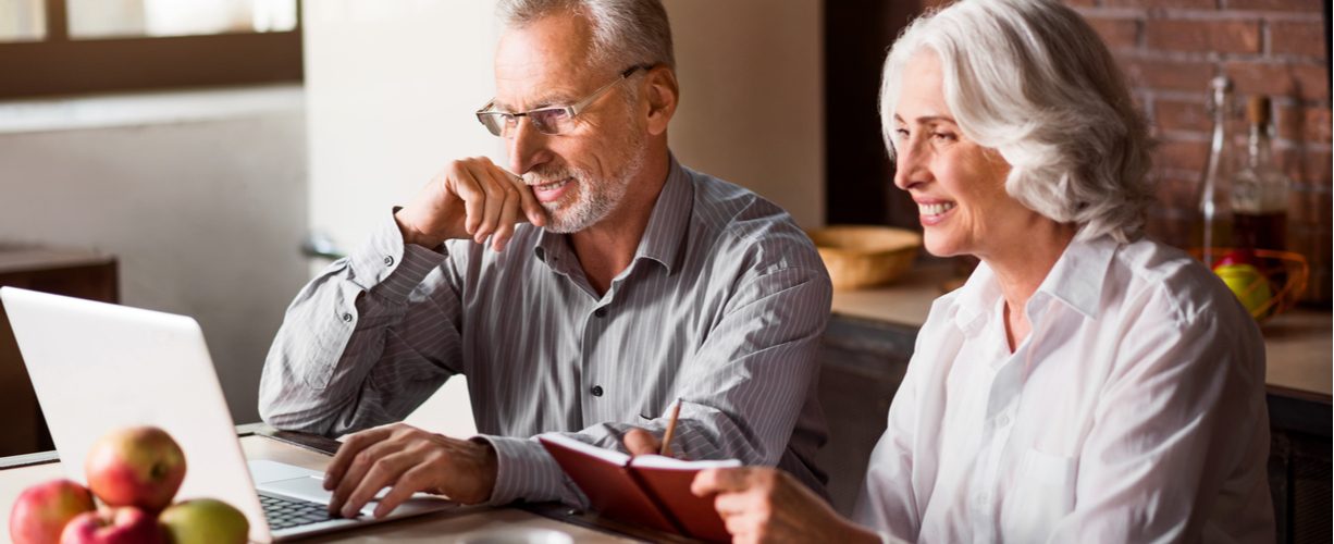 older couple smiling and looking at a laptop together