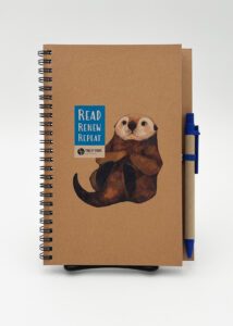 Spiral notebook with natural brown cover and cute otter illustration, with a pen