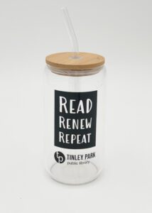 Glass tumbler with the words "read, renew, repeat" on the side, along with a wooden lid and glass straw