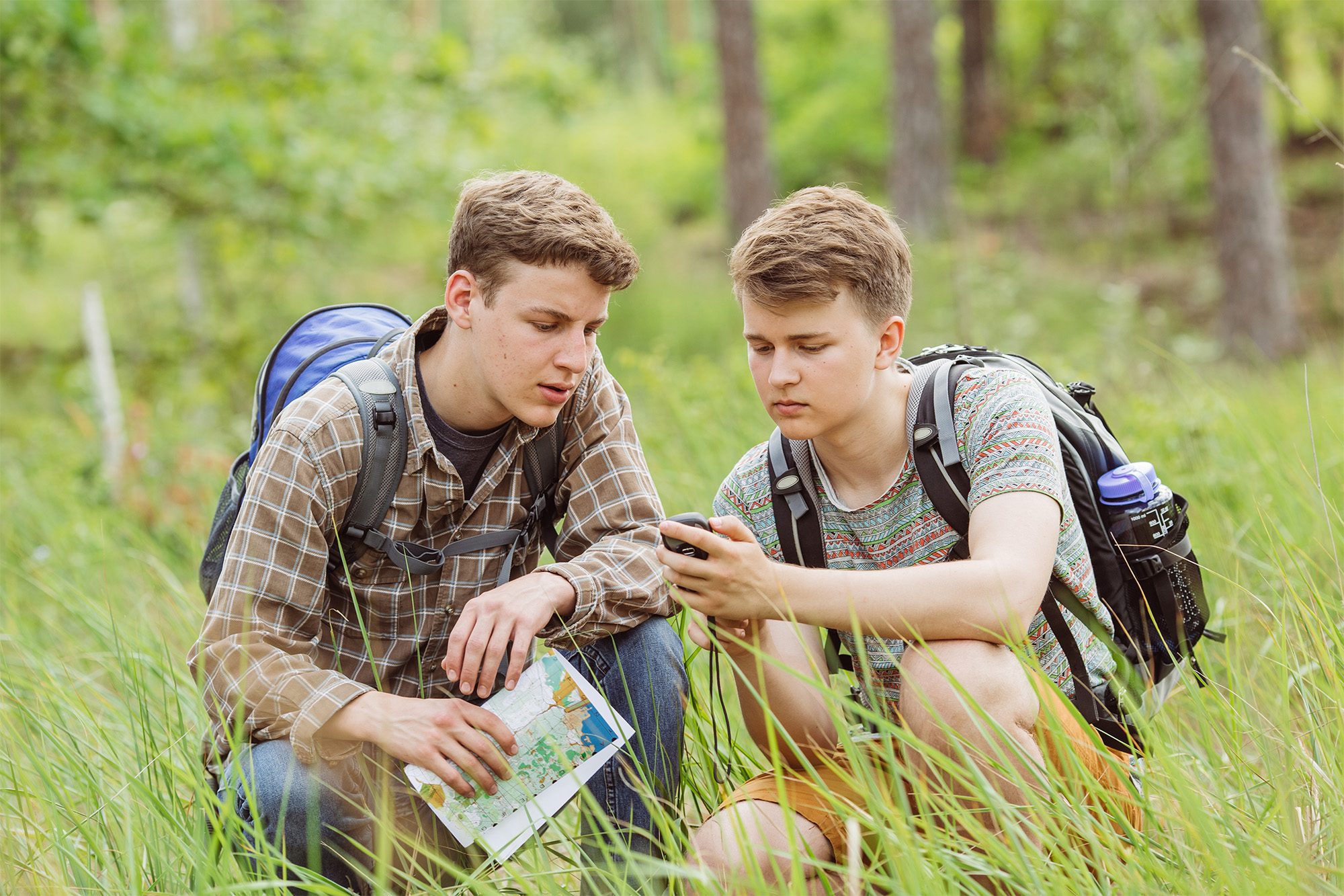 Two teenage boys geocaching outdoors