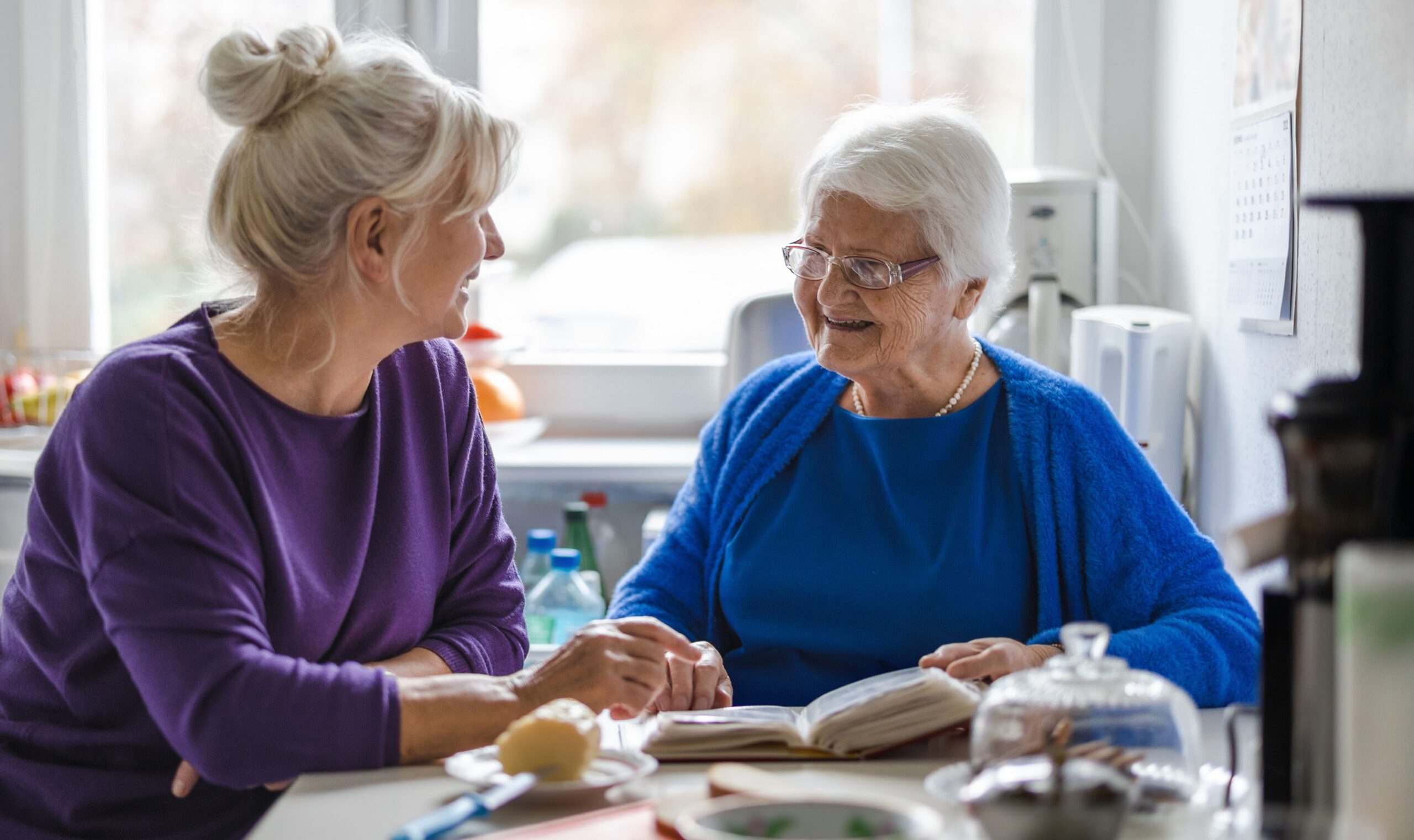 Adult woman and elderly woman at breakfast table, smiling and conversing